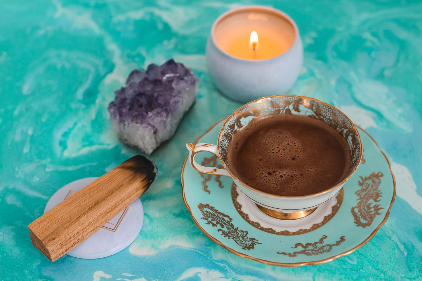 Une tasse de cacao dans une tasse décorative avec un cristal et un bâton de palo santo